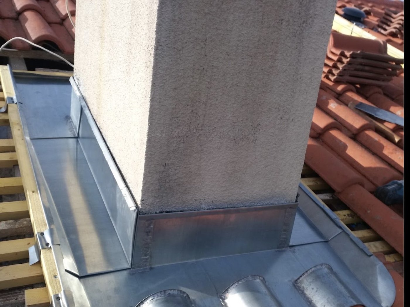 Solin en zinc soudé à la base d'une cheminée en brique, chantier BGR Couverture